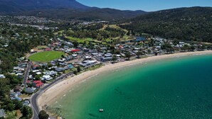 An aerial view of a coastal town with a beach, residential areas, and a mountain in the background. - Beach house with sauna. Stunning views, cosy renovated mid-century gem (Kingston Beach)