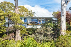 A two-story building with a balcony, surrounded by trees and vegetation. - Sjøro • Stunning Sea Views • Beach Access • Sauna (Kingston Beach)