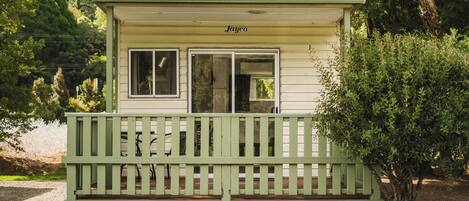 Een klein, gelijkvloers vakantiehuisje met een veranda en een raam.