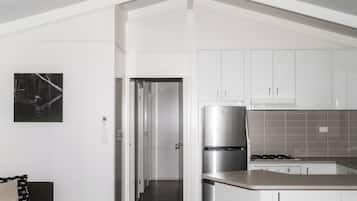 Een moderne keuken met witte kasten, een roestvrijstalen koelkast en een betegelde achterwand.