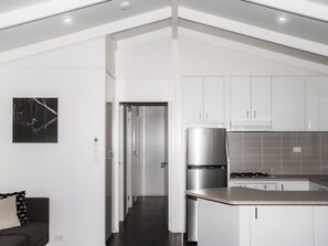 A modern kitchen with white cabinetry, a stainless steel refrigerator, and a tiled backsplash. - Warburton Holiday Park (Warburton)