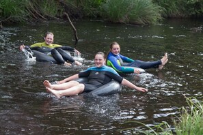 Tres personas flotando en un río con trajes de neopreno.