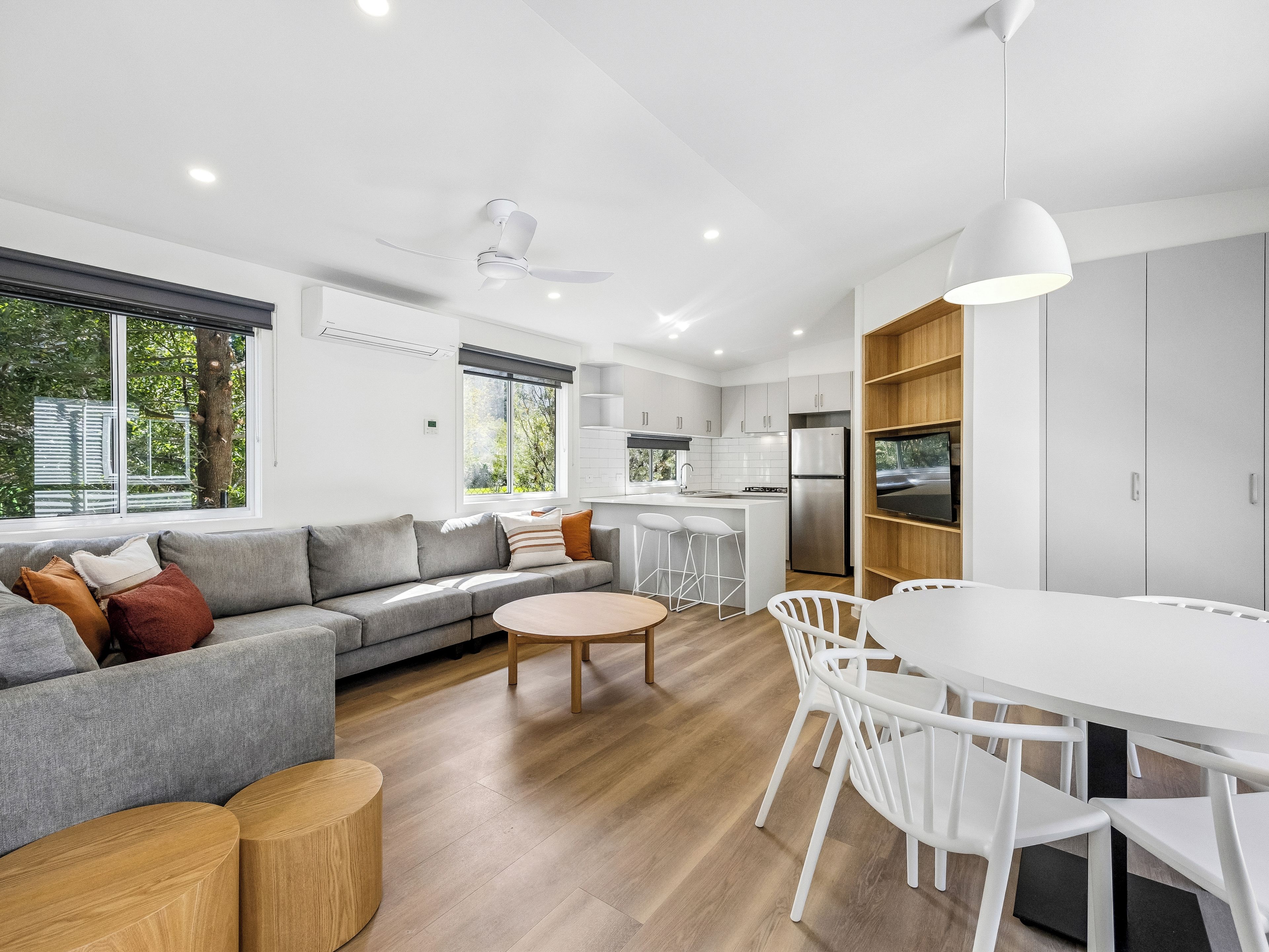 Een moderne keuken met witte kastjes, een roestvrijstalen koelkast en een eethoek met een witte tafel en stoelen.