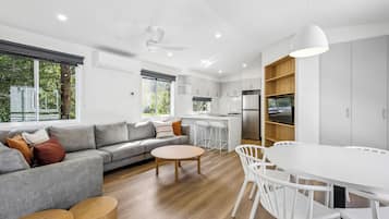 Een moderne keuken met witte kastjes, een roestvrijstalen koelkast en een eethoek met een witte tafel en stoelen.