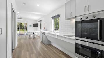 Una cocina moderna con electrodomésticos de acero inoxidable, lavavajillas y un amplio ventanal.