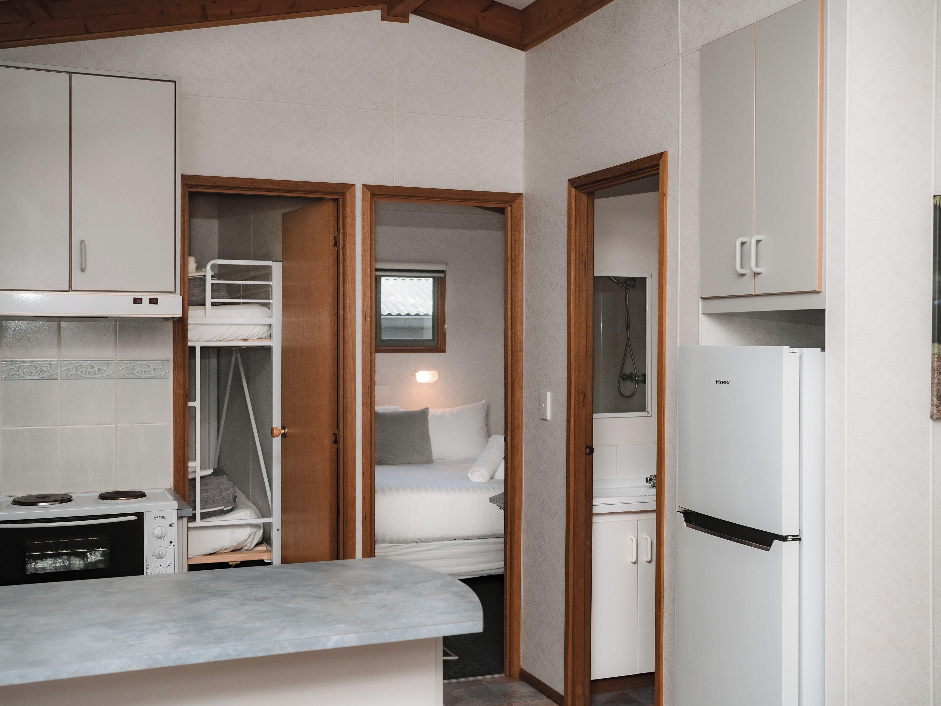 A compact kitchen with a stove, a refrigerator, and wooden cabinets.