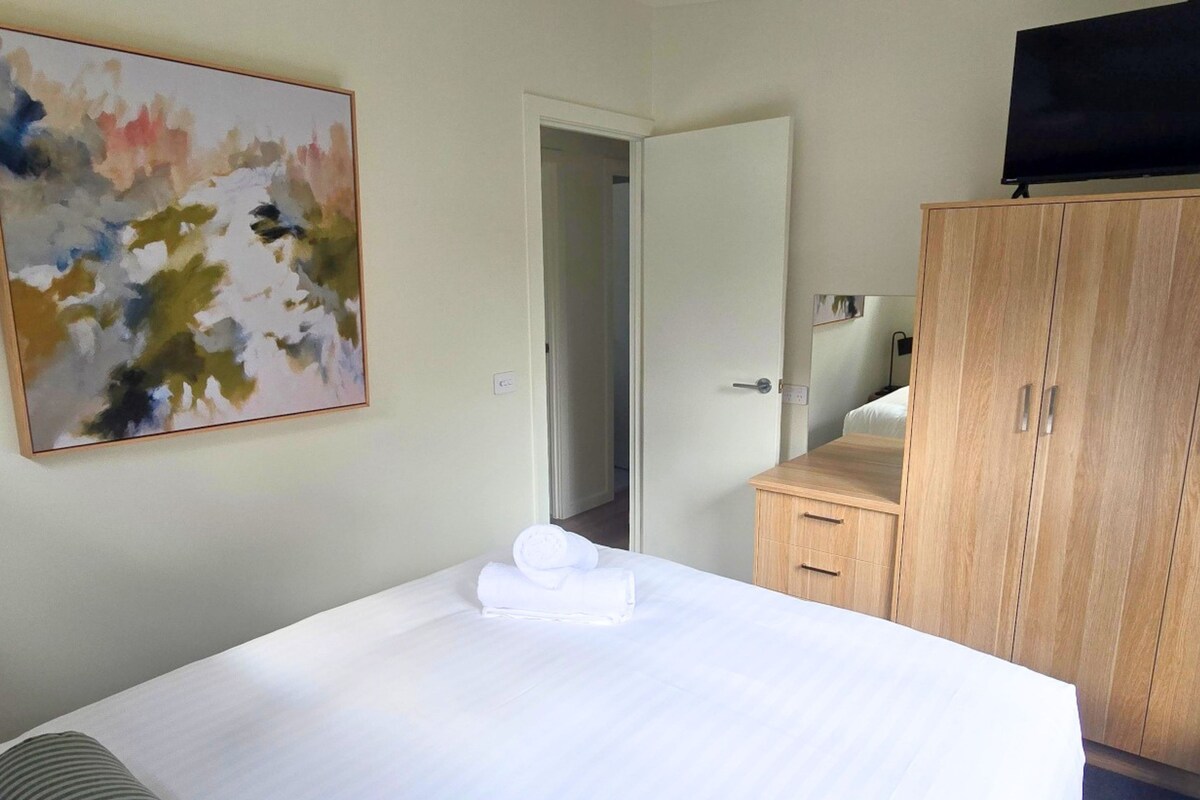 Habitación de hotel con cama, armario de madera, televisor y un cuadro en la pared.