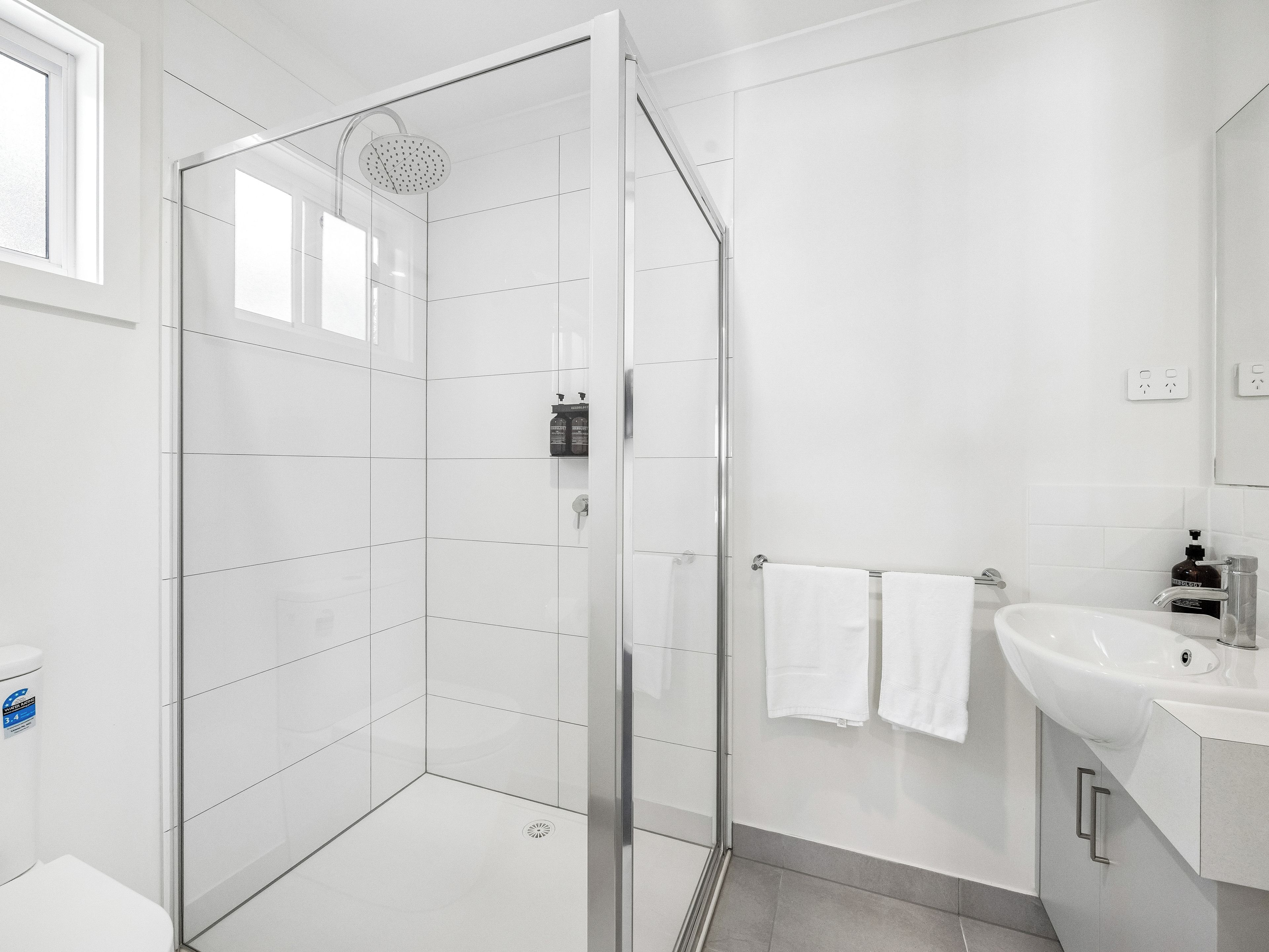 A modern bathroom with a glass shower enclosure, a white sink, and a toilet.