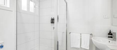 Une salle de bain moderne avec une douche à parois de verre, un lavabo blanc et des toilettes.