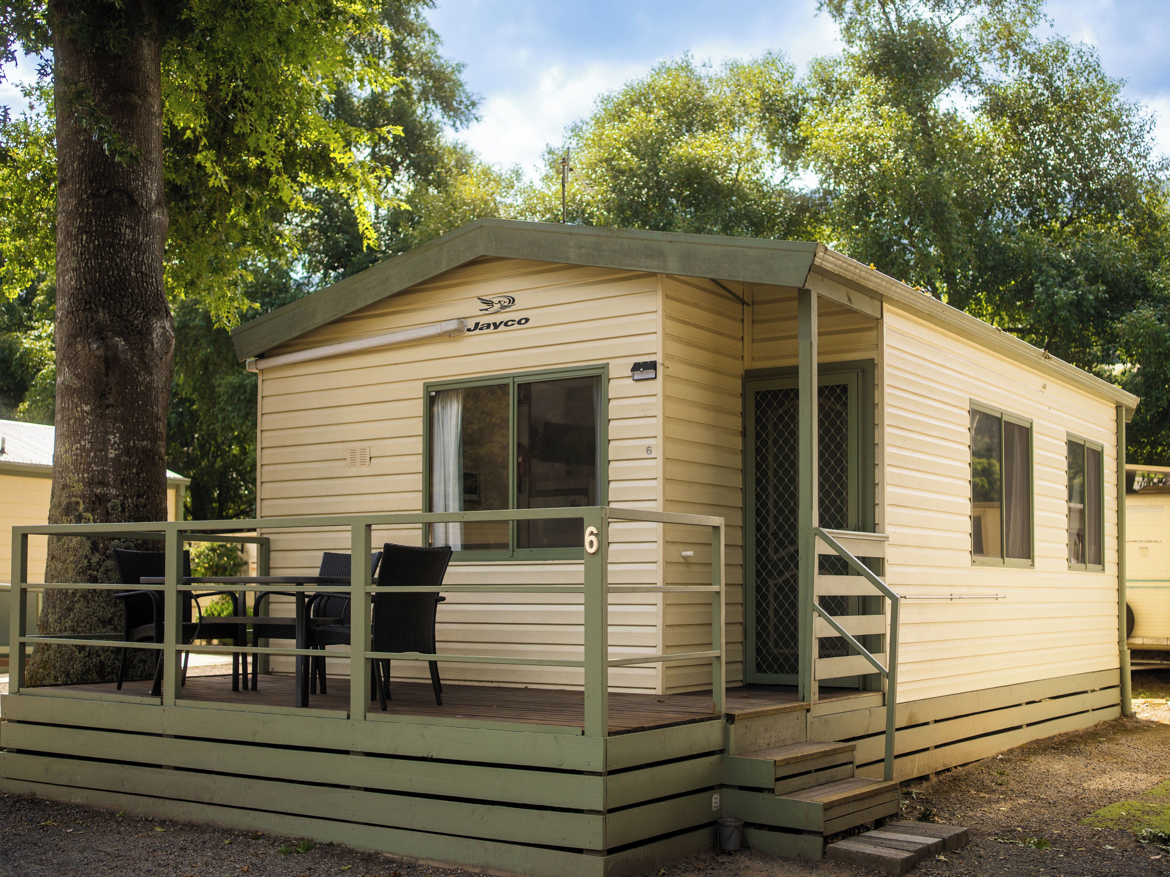 A small, single-story mobile home with a porch and two chairs.