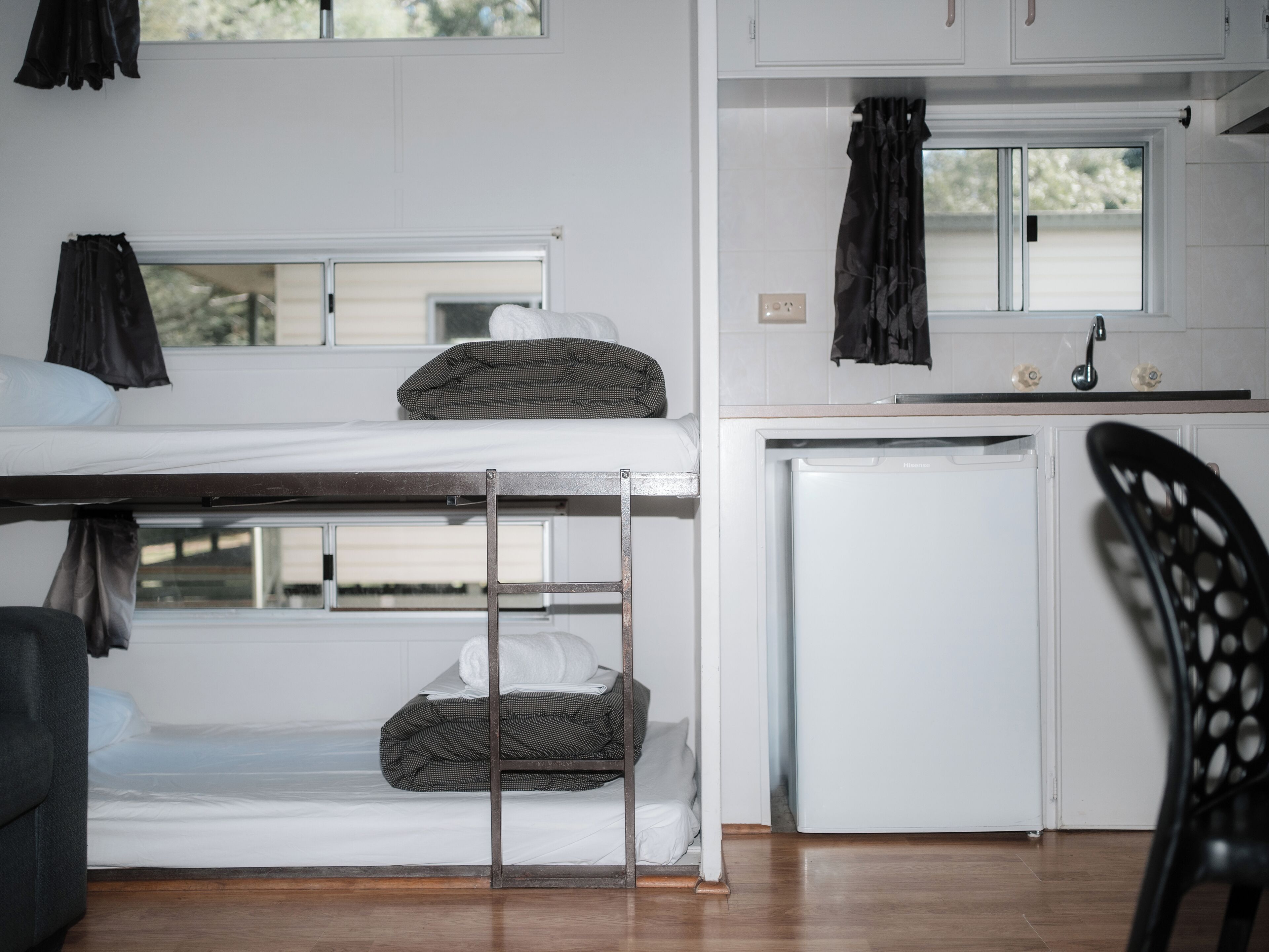 A bunk bed with a small kitchenette area, including a sink and a refrigerator.