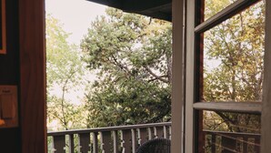 An open door leading to a balcony with wicker furniture and a table. - Art-Filled Casita, Walk to Plaza, Hottub & Pool (Santa Fe)