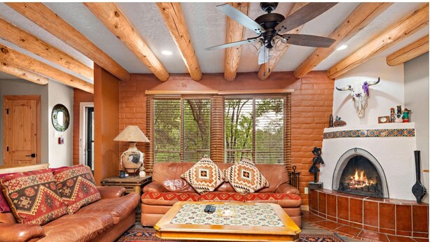 A cozy living room with a leather sofa, patterned cushions, a coffee table, and a fireplace. - Art-Filled Casita, Walk to Plaza, Hottub & Pool (Santa Fe)
