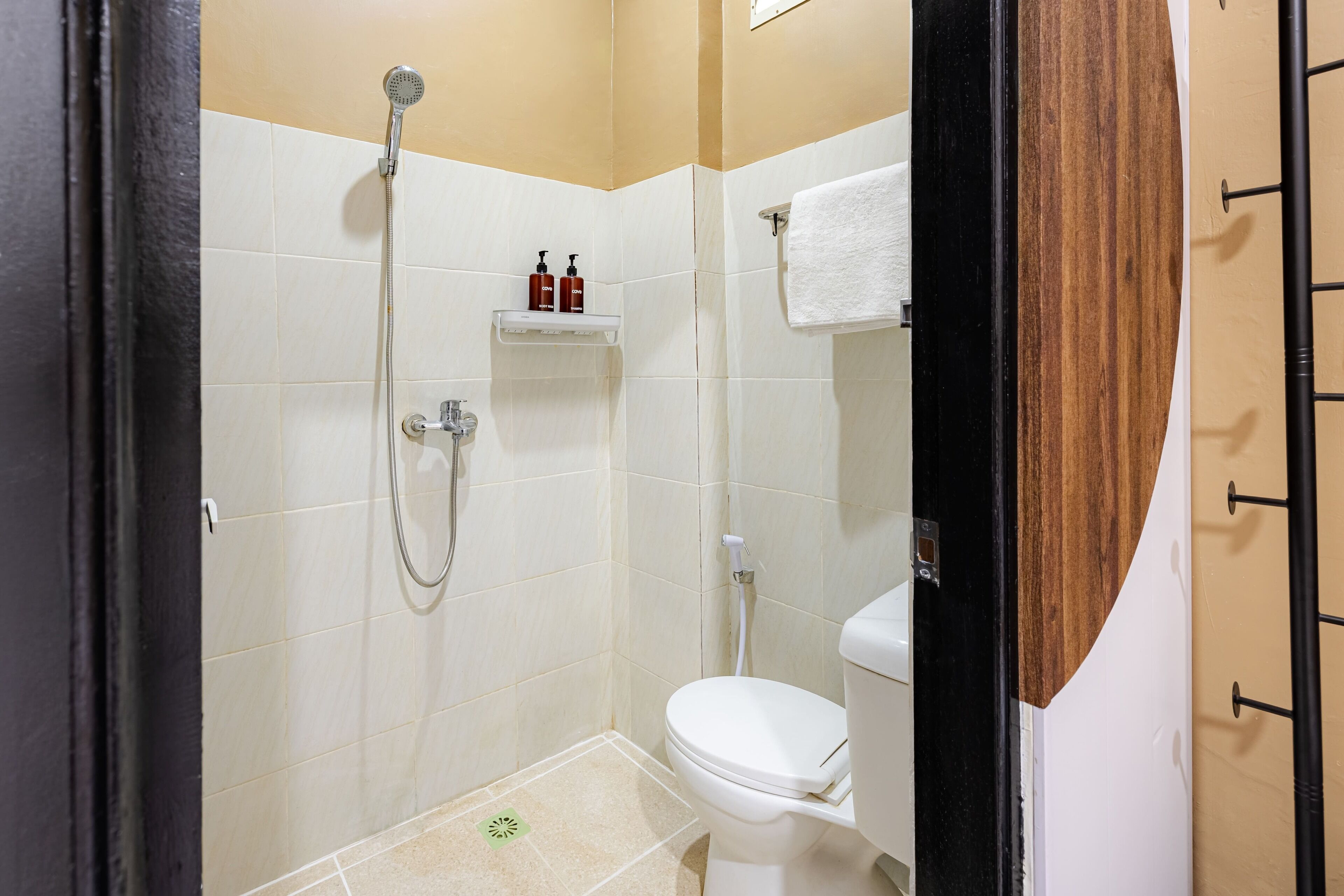 A small, modern bathroom with a shower, toilet, and a shelf with toiletries.