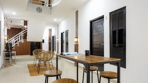 Um interior moderno com uma mesa de jantar de madeira, quatro banquetes e uma escada que leva a um andar superior.