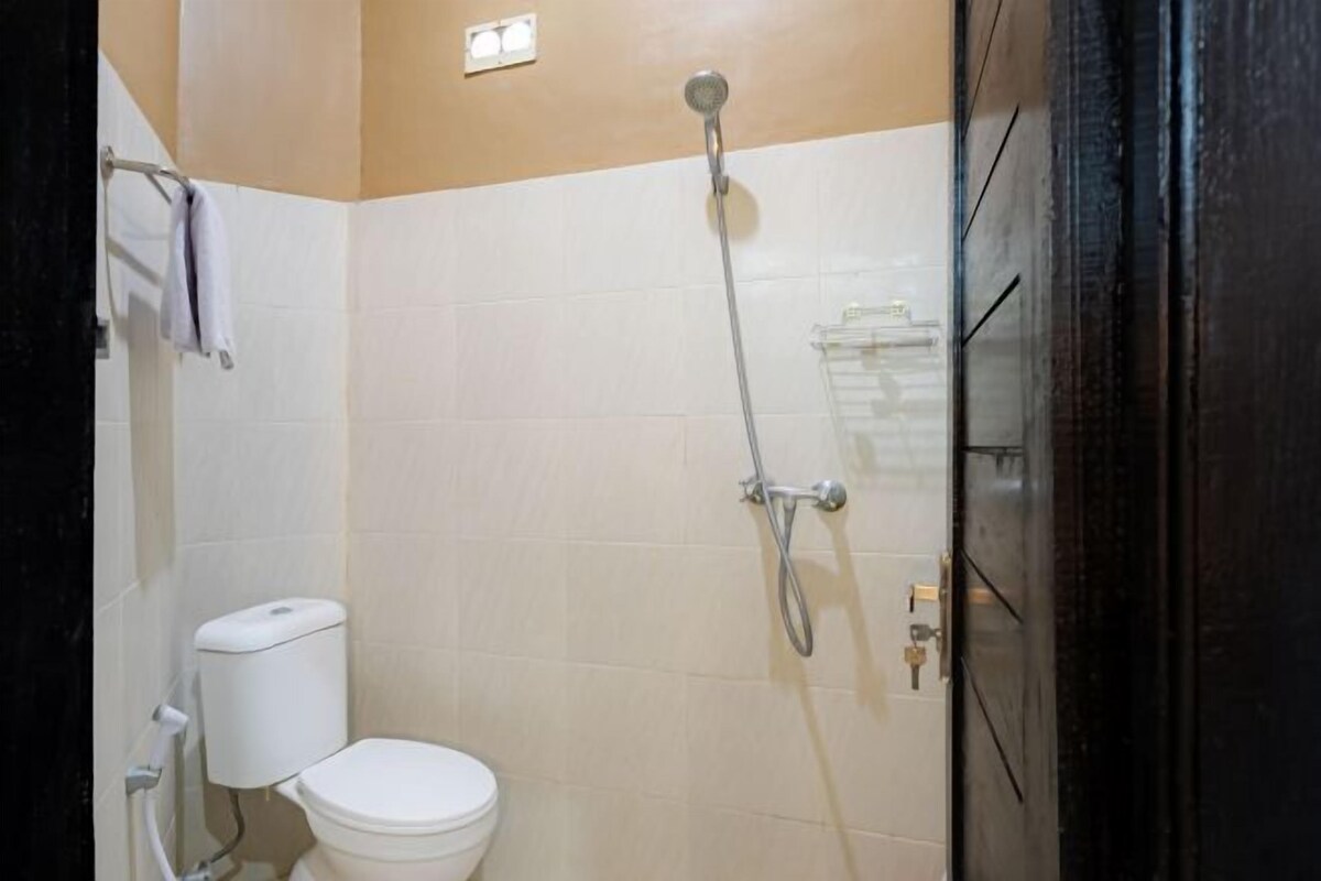 A small bathroom with a toilet, a shower, and a towel rack.