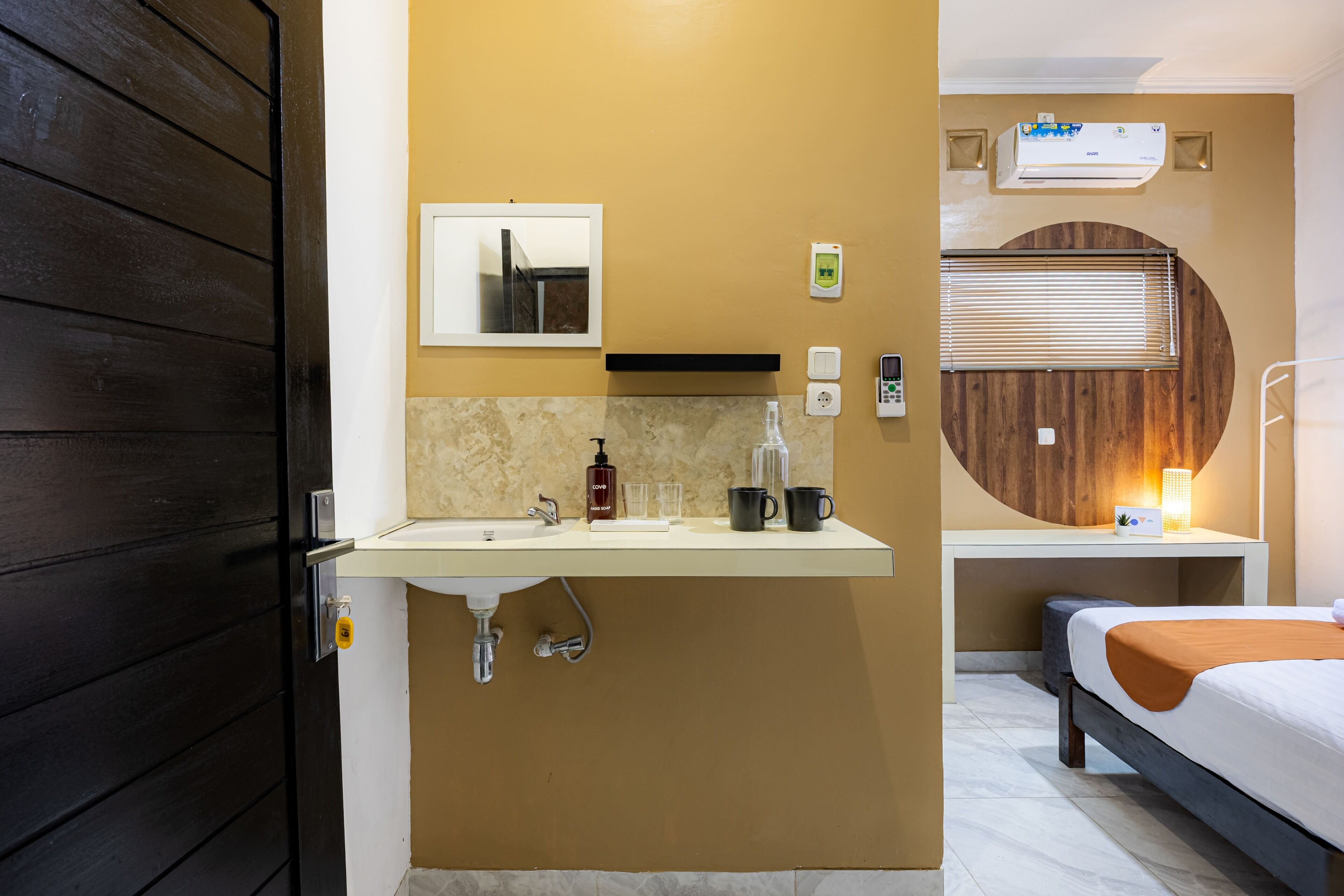 Un baño de hotel con lavamanos, espejo, toallero y una pared decorativa circular de madera.