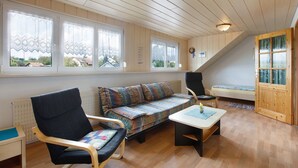 Una habitación con techo de madera, un sofá, una silla, una mesita y una ventana con vistas.