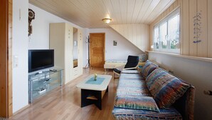 Una habitación con televisión, sofá y techo de madera.
