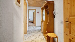 Un pasillo con puerta de madera, una mesita y un espejo.
