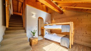 Een houten cabin interieur met een stapelbed, een trap en een klein nachtkastje met een plant.