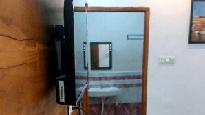 A wooden bench with a television mounted on the wall. - New View Inn (Varanasi)