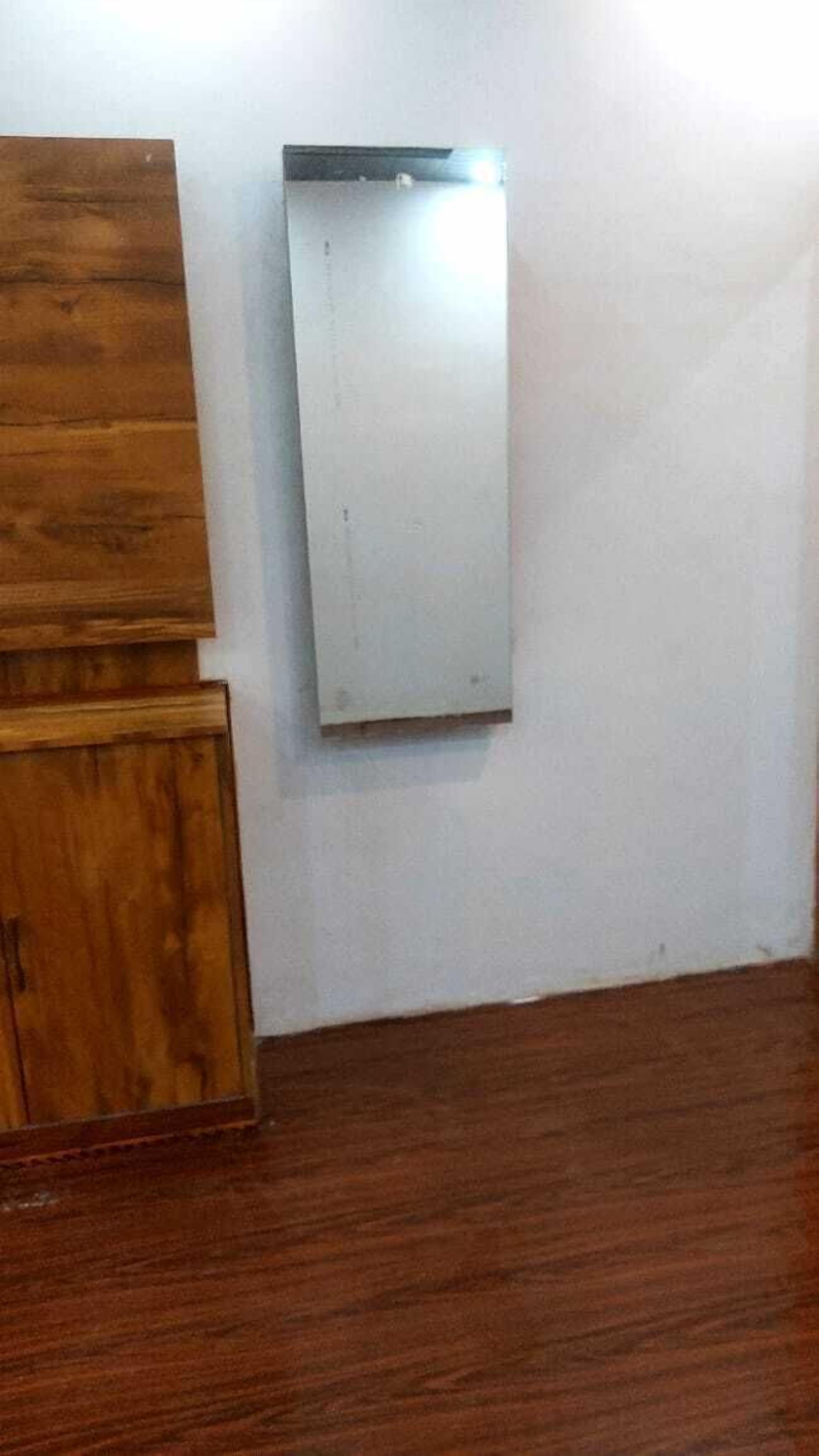 A room with a wooden cabinet and a white wall-mounted panel.