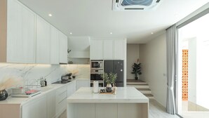 Una cocina moderna con armarios blancos, encimera de mármol y electrodomésticos integrados.