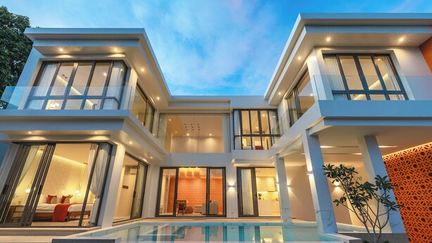 Una casa moderna de varios pisos con piscina, amplias ventanas y un interior bien iluminado.