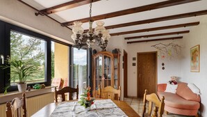 A dining area with a wooden table, chairs, a chandelier, a cabinet, and a pink sofa.