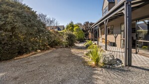 Une allée de gravier mène à une maison moderne dotée d’un porche abrité et d’un jardin.