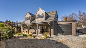 Une maison à deux étages avec un porche couvert, un garage et une allée gravillonnée.