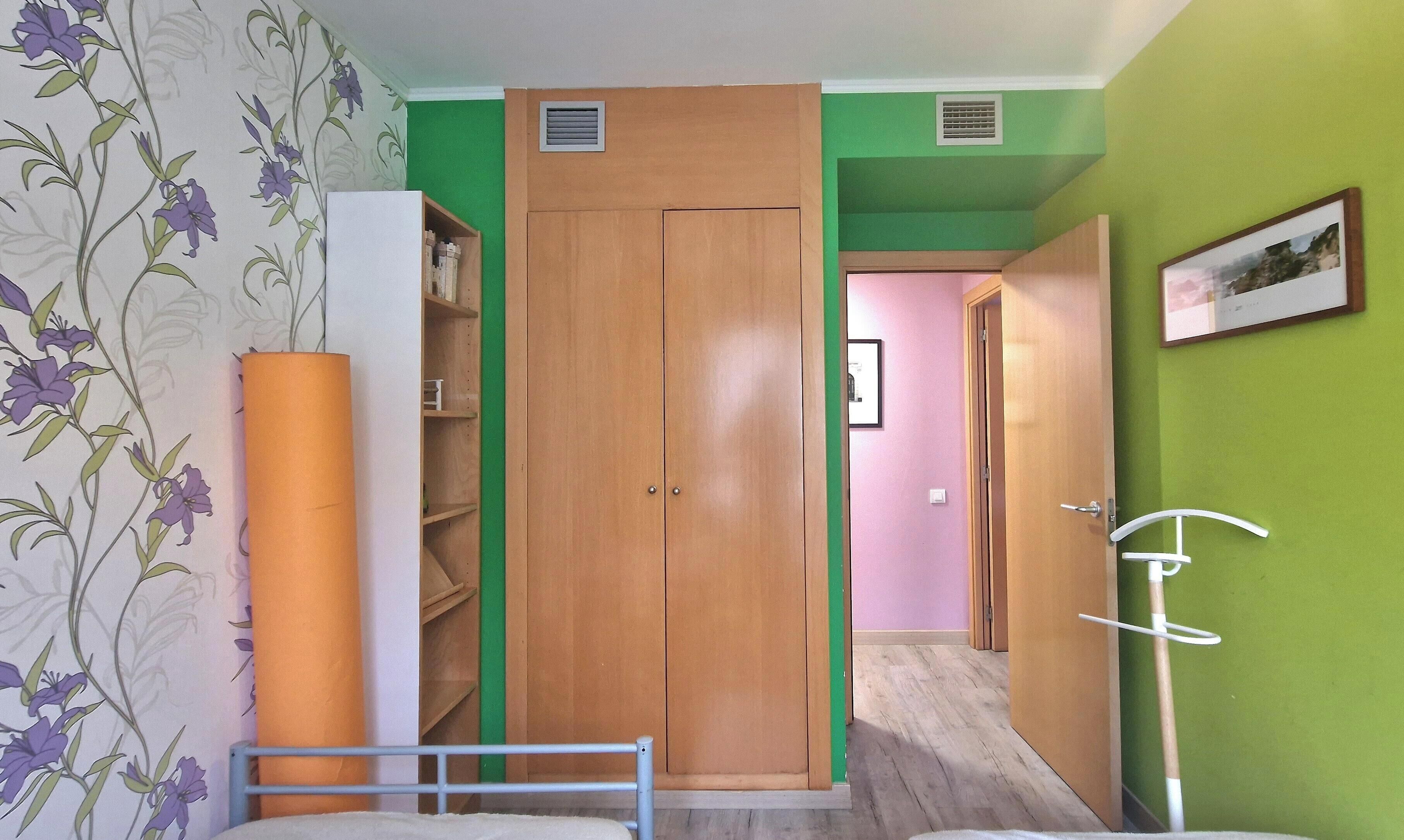 Quarto com guarda-roupa, cama, mesa de cabeceira e um quadro pendurado na parede.