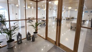 A spacious, modern interior with large glass doors leading to a dining area. - Hotel YJ Manor (Dehradun)