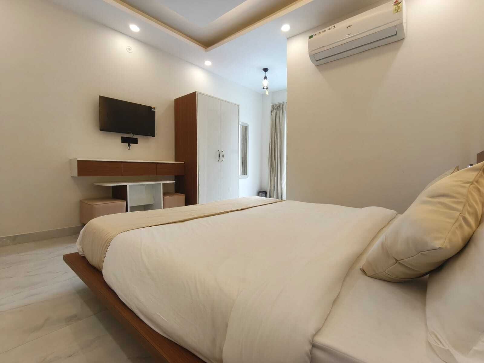 Un dormitorio moderno con una cama grande, un televisor montado en la pared y un armario empotrado.
