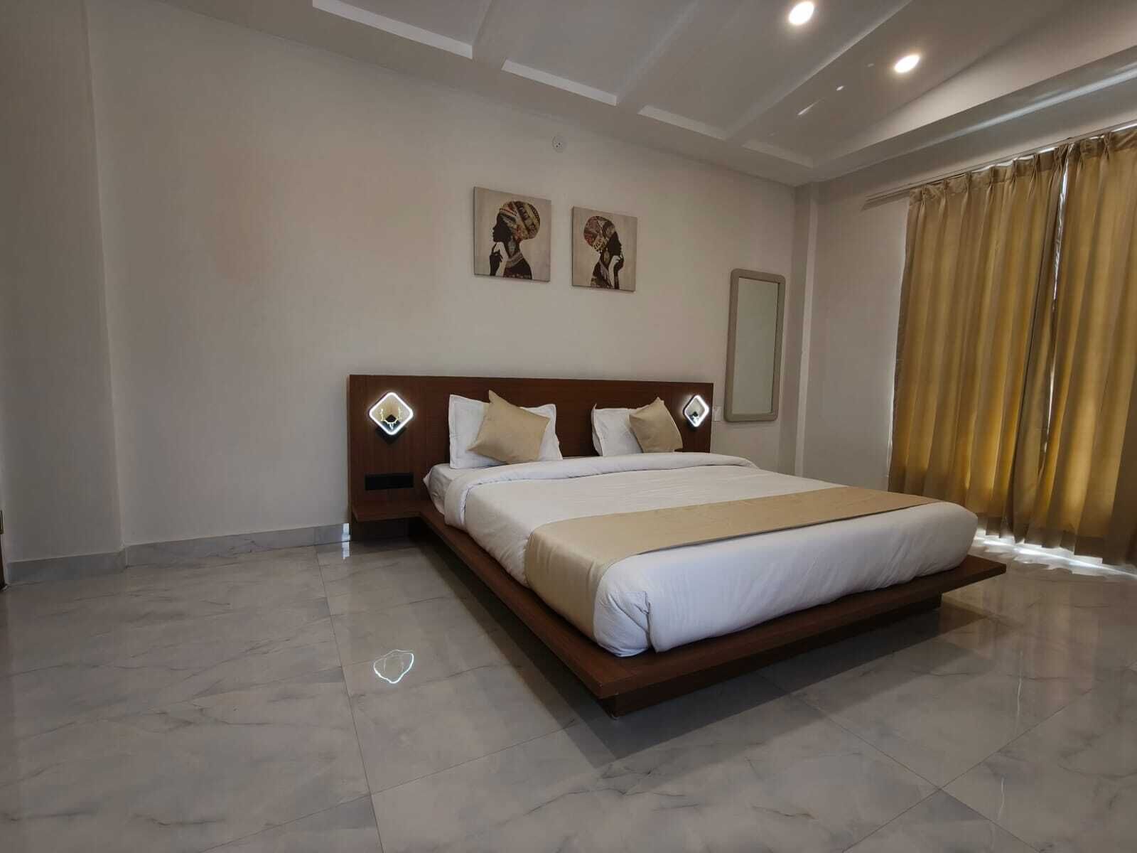 Un ampio letto con testiera in legno, due luci a parete e due opere d'arte incorniciate sopra.