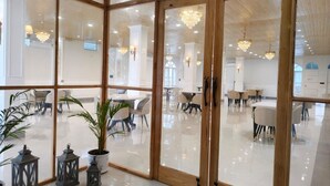 Un vestíbulo amplio con mobiliario moderno, un candelabro y un gran ventanal que da a otra zona.