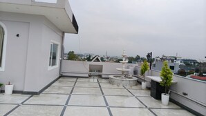Una terraza en la azotea con una fuente, plantas en macetas y vistas de la ciudad.