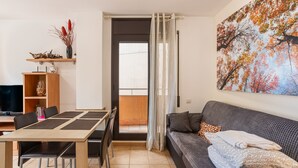Een moderne woonkamer met een bank, een eettafel met stoelen, een televisie en een schilderij aan de muur.