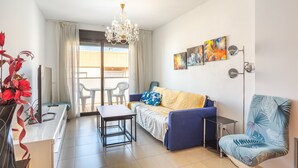 A modern living room with a sofa, a table, a chair, a TV, and artwork on the wall. - Apartment 'Verano Go2lloret' with Mountain View, Wi-Fi and Air Conditioning (Lloret de Mar)
