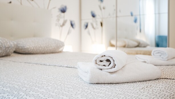 A neatly arranged bathroom with towels, a patterned floor, and a wall with floral decorations. - Apartment 'Verano Go2lloret' with Mountain View, Wi-Fi and Air Conditioning (Lloret de Mar)