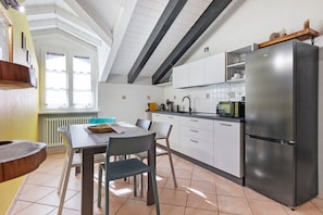 Een keuken met witte kastjes, een roestvrijstalen koelkast en een eettafel met stoelen.