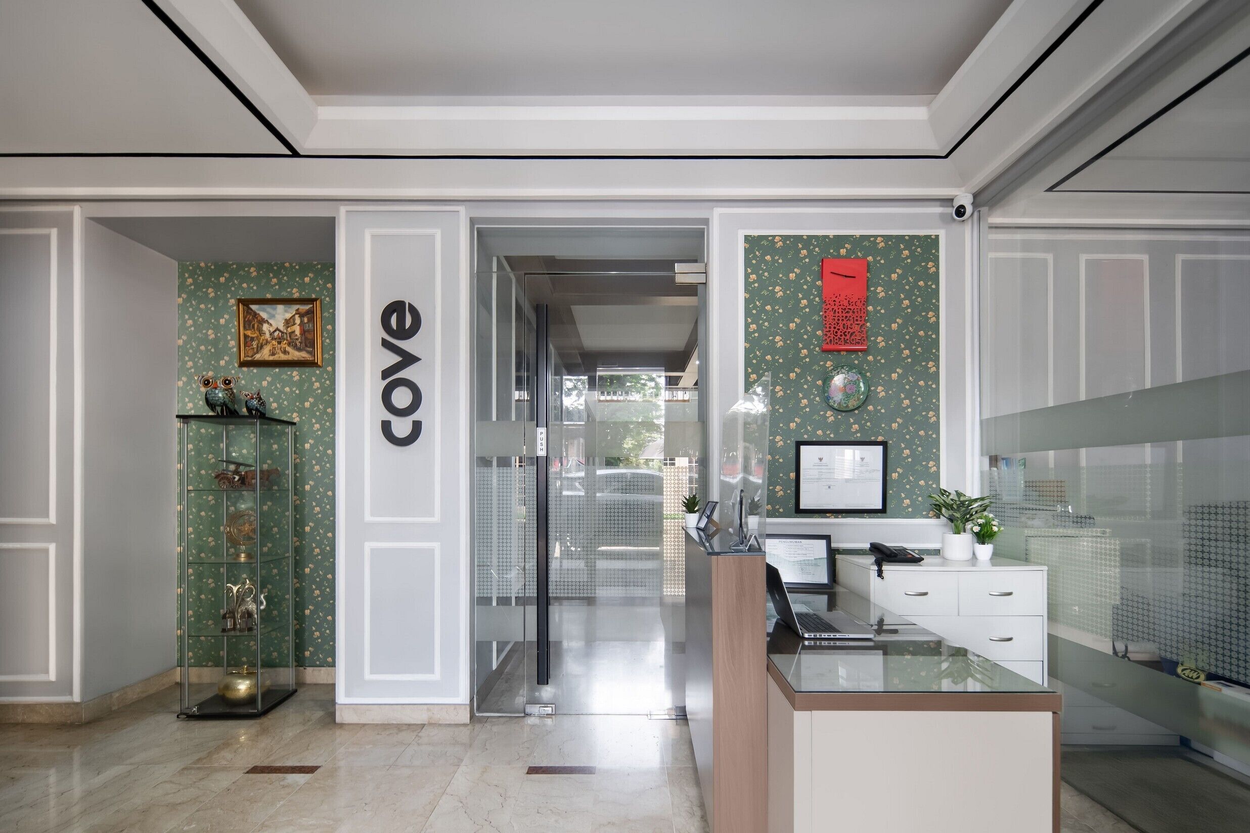 A reception area with a glass partition, a reception desk, and a wall-mounted sign.