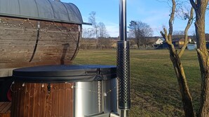 Un entorno rústico al aire libre con una estructura de madera, una chimenea de metal y un árbol.