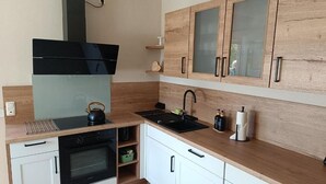 Una cocina moderna con horno empotrado, campana extractora negra y armarios de madera con puertas de vidrio.