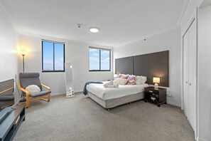 A modern bedroom with a large bed, a chair, a bedside table, and a lamp. - Central Studio | Walk to River, Shops & Dining (Brisbane)