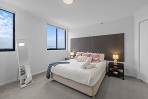 A modern bedroom with a large bed, bedside lamps, a nightstand, a window, and a built-in shelf. - Central Studio | Walk to River, Shops & Dining (Brisbane)