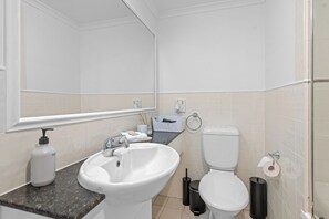 A modern bathroom with a white sink, a toilet, and a large mirror. - Central Studio | Walk to River, Shops & Dining (Brisbane)