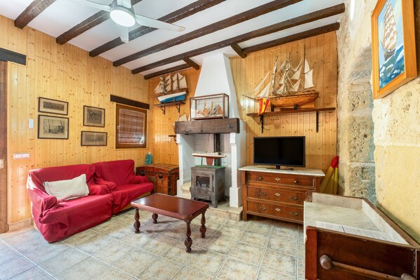 Un salón amueblado con madera, que incluye un sofá rojo, una mesa de centro de madera, un televisor y un modelo de barco.