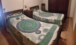 Two beds with patterned bedding, a bedside table with a lamp, and a wooden wardrobe. - Casa Bohemio - Tabarca (Tabarca)